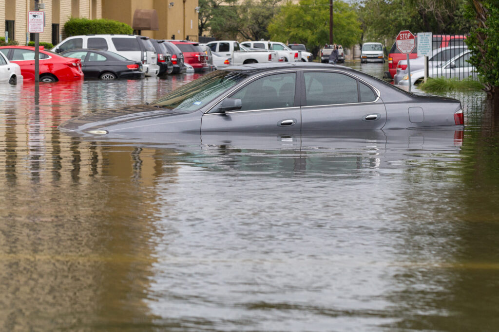 Floodwater covering a suburban residential street and front yards after heavy flooding